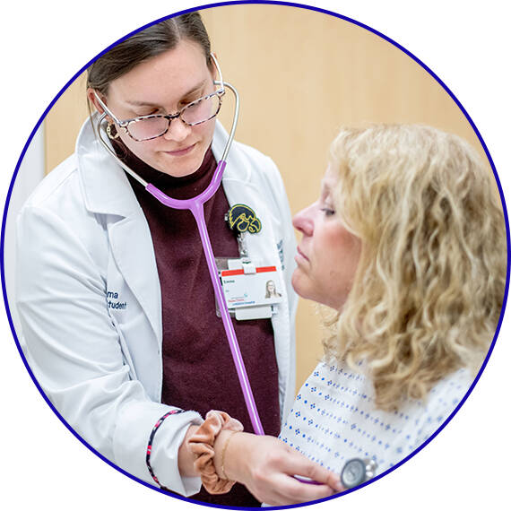 DNP students listening to a Standardized Patient's lung sounds.